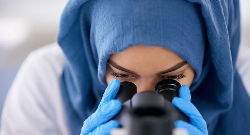 调查显微镜的女性科学家。