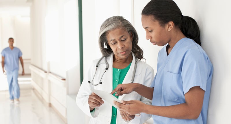 一位女性医生和护士在走廊谈论文件