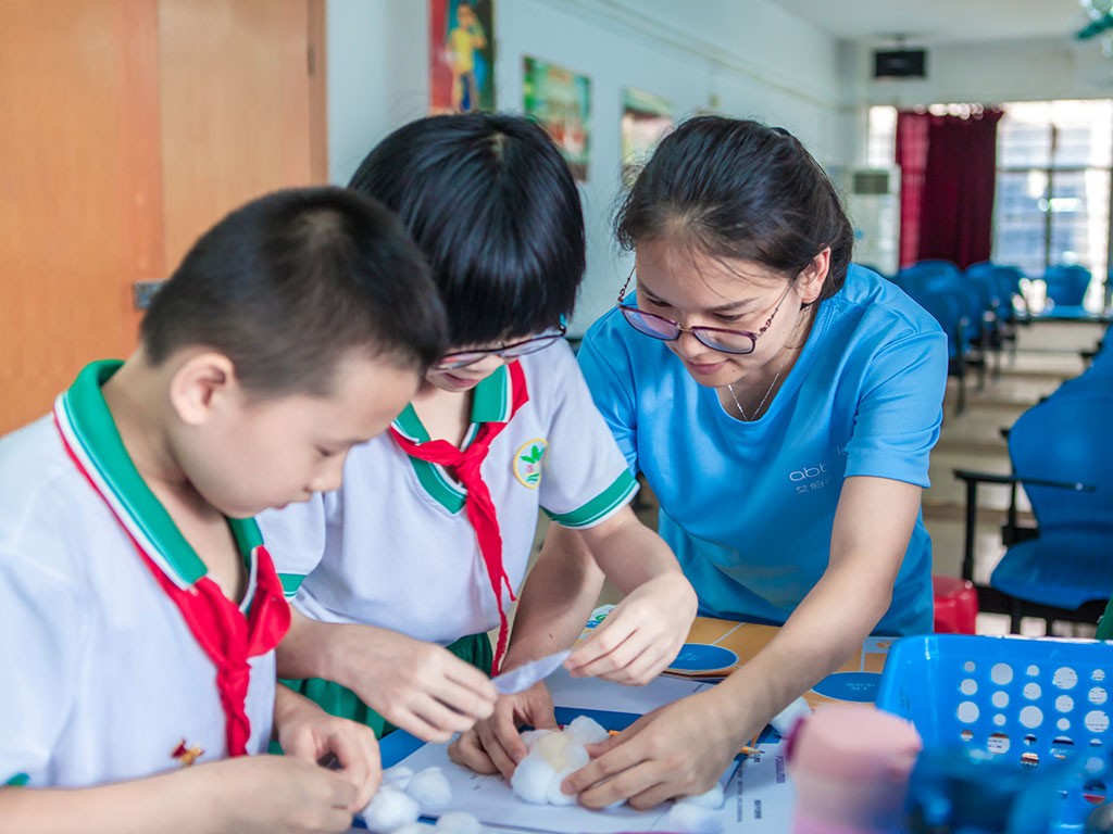 一个妇女在帮助两个孩子做科学实验